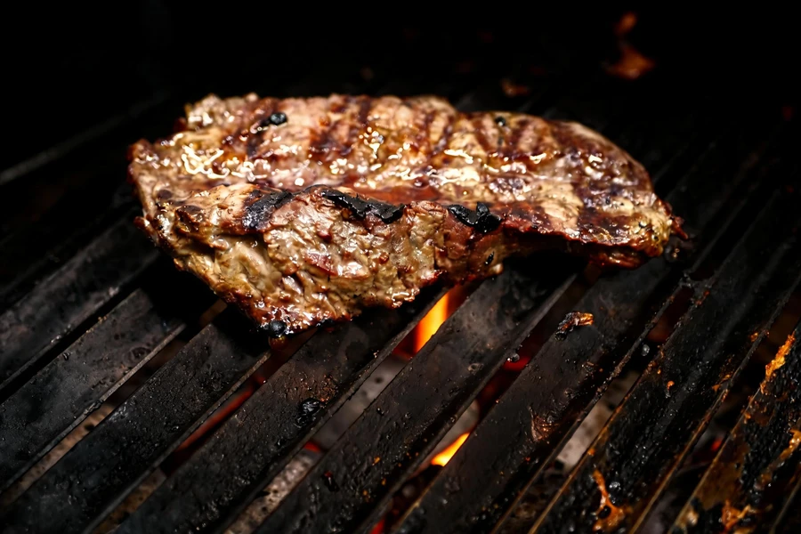 Steak with grill marks over glowing charcoal at Parejas Altlandsberg
